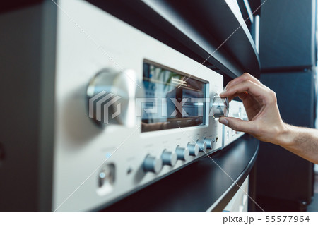 Hand of woman turning up volume of Hi-Fi amplifier 55577964