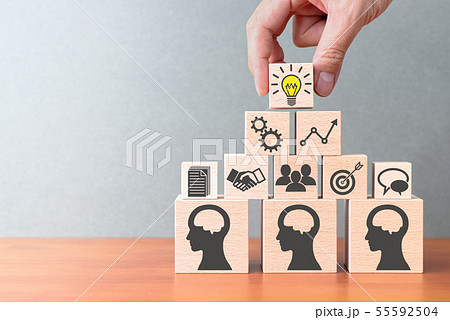 知識の共有とマネジメント。テーブルの上で積み木を積む手のアップ。 55592504
