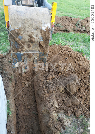 The excavator digs a small trench in the yard. 55601483