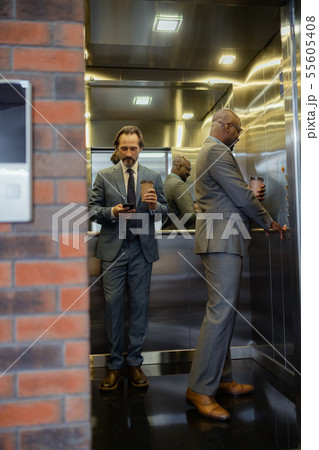 Businessmen holding coffee using elevator in business center 55605408