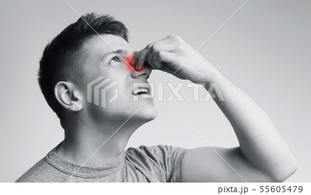 Young man suffering from nose bleeding, black and white Young man suffering from nose bleeding, black and white 55605479