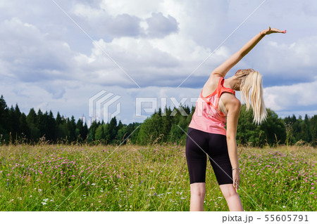 young woman doing exercises stretching in a meadow young woman doing exercises stretching in a meadow 55605791