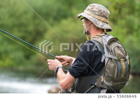 Fisherman fishing on the River, holding Fishing Rod. Fisherman fishing on the River, holding Fishing Rod. 55606649