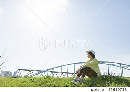 土手に座るスポーツウェア姿の女性の写真素材