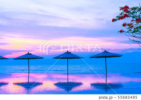 Umbrella and chair around swimming pool neary sea ocean beach at sunrise or sunset time 55683495