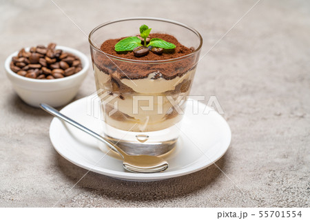 Classic tiramisu dessert in a glass cup on plate and coffee beans on concrete background 55701554