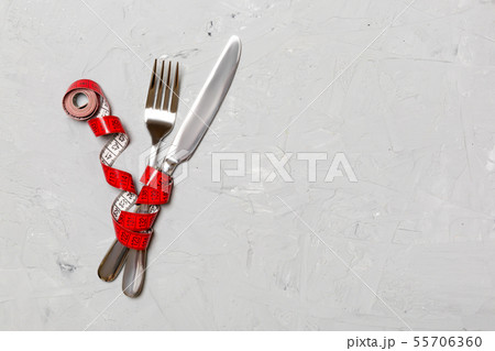 Crossed fork and knife are wrapped in measuring Crossed fork and knife are wrapped in measuring 55706360