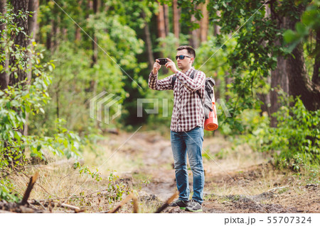 Man hiker taking photo smart phone in forest. Attractive Traveler Making Photo With Mobile Phone 55707324