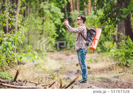 Man hiker taking photo smart phone in forest. Attractive Traveler Making Photo With Mobile Phone 55707326