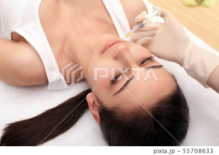 Hands of cosmetologist making injection in face, lips. Young woman gets beauty facial injections in 55708633