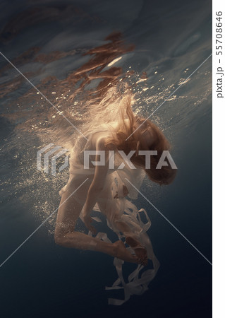 Girl in a dress with ribbons swims underwater 55708646