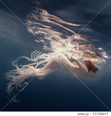Girl in a dress with ribbons swims underwater 55708647