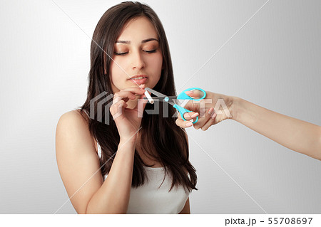 Stop smoking concept. Young woman cut cigarettes with scissors happy smiling. focus on hand Stop smoking concept. Young woman cut cigarettes with scissors happy smiling. focus on hand 55708697