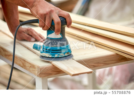 Grinder worker polishes a wooden board. Sanding boards Orbital eccentric machine. Grinder worker polishes a wooden board. Sanding boards Orbital eccentric machine. 55708876