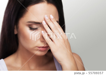 Headache. A tired, exhausted young woman who suffers from a severe headache of tension. Portrait of Headache. A tired, exhausted young woman who suffers from a severe headache of tension. Portrait of 55709357