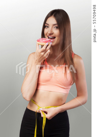 Slender girl. A young woman measuring her thin waist with a ribbon. Diet and Sports. The concept of Slender girl. A young woman measuring her thin waist with a ribbon. Diet and Sports. The concept of 55709498