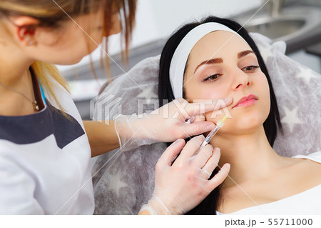 Woman gets injection in her face. Beauty woman giving injections. Young woman gets beauty facial Woman gets injection in her face. Beauty woman giving injections. Young woman gets beauty facial 55711000