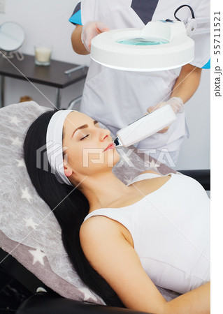 Cosmetology. Ultrasonic face cleaning, peeling, in a beauty salon. Beautiful Woman Receiving Facial Cosmetology. Ultrasonic face cleaning, peeling, in a beauty salon. Beautiful Woman Receiving Facial 55711521