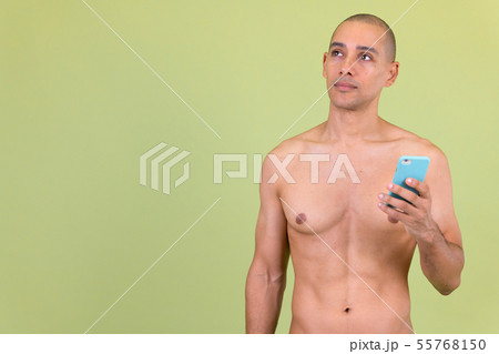 Handsome bald multi ethnic man thinking while using phone shirtless Handsome bald multi ethnic man thinking while using phone shirtless 55768150