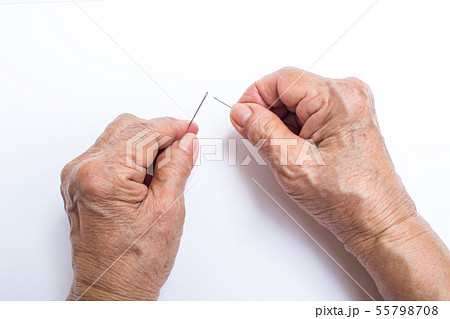 Senior woman's hands trying to thread a needle 55798708