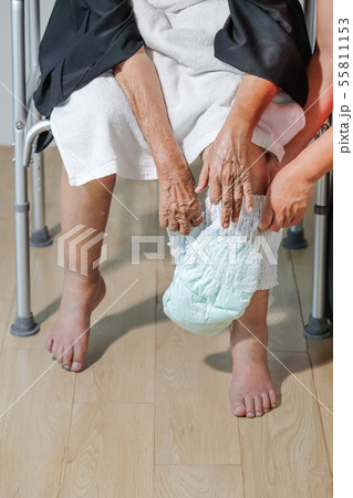 elderly woman changing diaper with caregiver 55811153