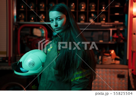 Image of woman firefighter with long hair with helmet in her hands at fire station. 55825504