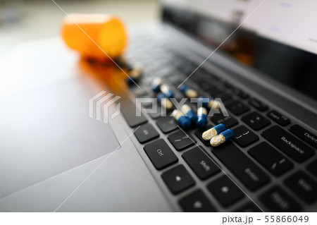 Yellow-blue pill capsules are scattered on black 55866049