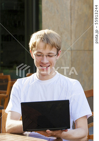 Young man checking mail in cafe on the street in summer day 55913244