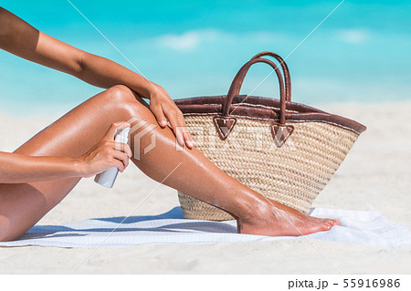 Sunscreen beach woman putting sunblock oil on legs Sunscreen beach woman putting sunblock oil on legs 55916986