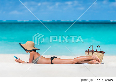 Beach vacation woman texting sms using phone app Beach vacation woman texting sms using phone app 55916989