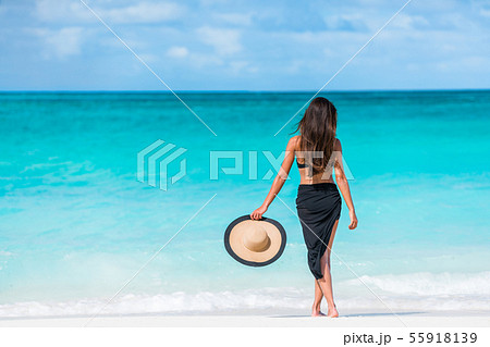 Woman in black bikini and sarong standing on beach 55918139