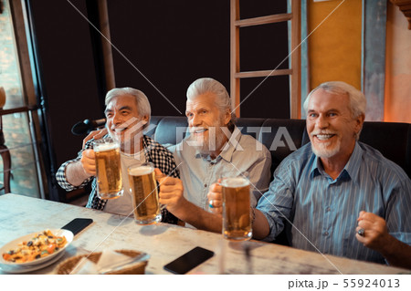 Beaming pensioners drinking beer and watching football Beaming pensioners drinking beer and watching football 55924013