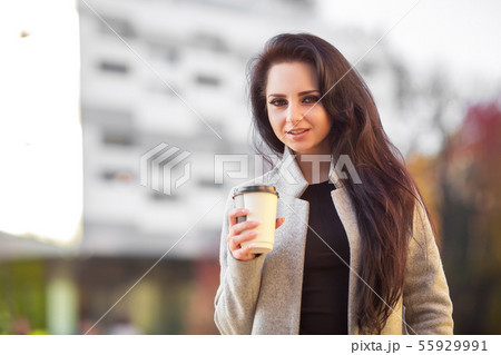Outdoors portrait of cheerful beautiful brunette woman expresses happy emotions. Coffee to go 55929991