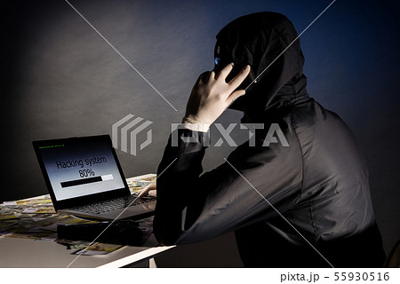 Anonymous hacker in mask sitting sideways uses a 55930516