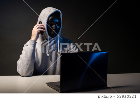 Anonymous hacker in mask programmer uses a laptop 55930521
