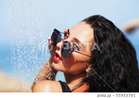 Tenned beautiful woman in black bikini and sunlasses sitting in swimming pool with cocktail Tenned beautiful woman in black bikini and sunlasses sitting in swimming pool with cocktail 55933701