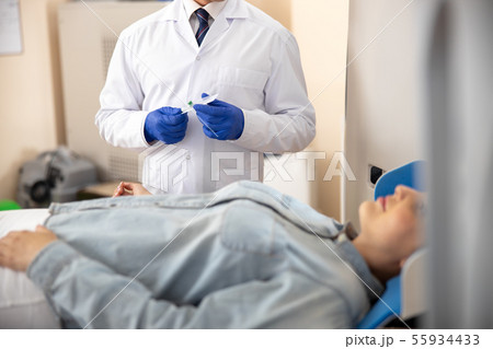 Doctor standing next to patient and holding catheter Doctor standing next to patient and holding catheter 55934433