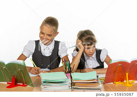 Two schoolgirls at a desk, one excellent student, 55935097