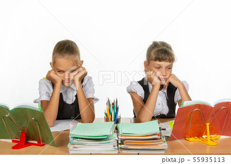 Sad schoolgirls look at textbooks in class 55935113