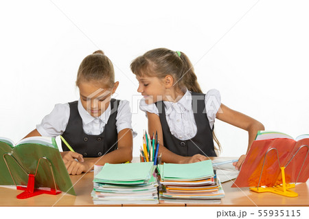 Girl looks at what her desk neighbor writes in a Girl looks at what her desk neighbor writes in a 55935115