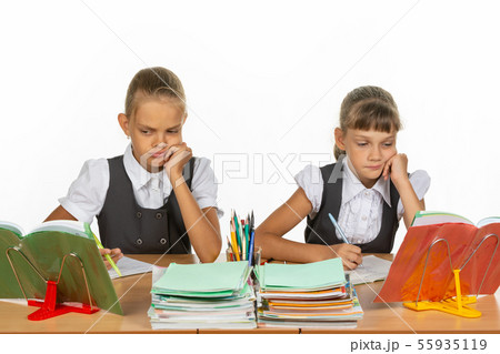Sad schoolgirls look at a book in a lesson Sad schoolgirls look at a book in a lesson 55935119
