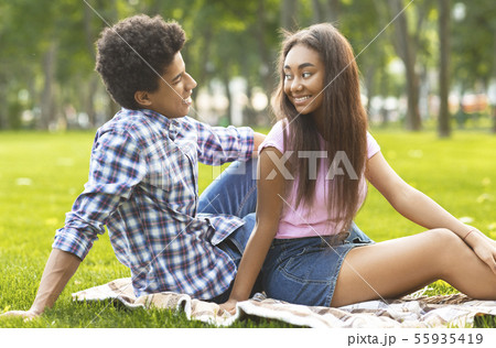 Happy teenage couple resting in park, looking at each other 55935419