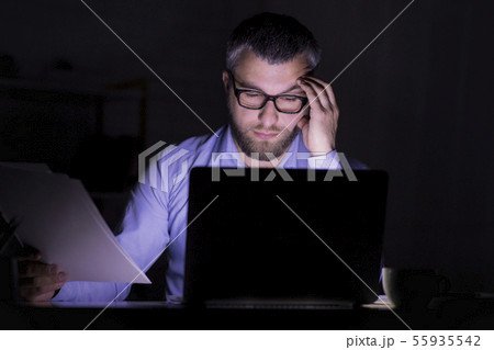 Bearded businessman is doing paper work in front of laptop Bearded businessman is doing paper work in front of laptop 55935542