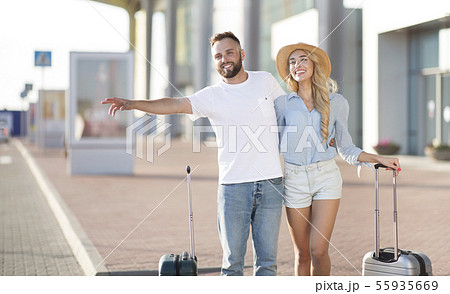 Young couple standing near airport trying to stop car 55935669