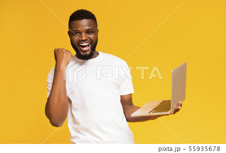 Excited african man celebrating win with laptop Excited african man celebrating win with laptop 55935678