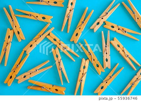 Wooden yellow clothespins are scattered on a cyan-blue background. Frame of clothespins. View from 55936746