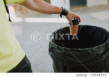 Man throwing paper cup into rubbish bin Man throwing paper cup into rubbish bin 55938377