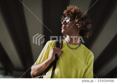 Smiling curly young man carrying black backpack 55938486