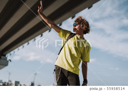 Curly young man putting hand forward and hiding from sun Curly young man putting hand forward and hiding from sun 55938514