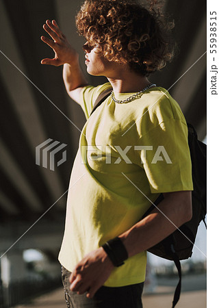 Curly student hiding from sun with hand in front of the face Curly student hiding from sun with hand in front of the face 55938515